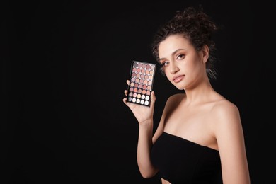 Photo of Woman with eyeshadow palette on black background. Space for text