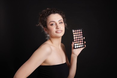 Photo of Woman with eyeshadow palette on black background