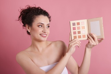 Photo of Smiling woman with eyeshadow palette on pink background