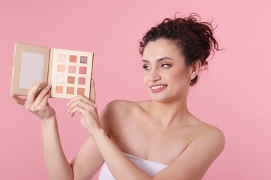 Photo of Smiling woman with eyeshadow palette on pink background