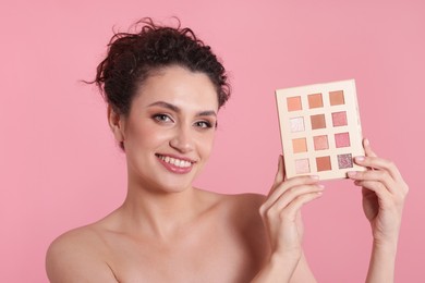 Photo of Smiling woman with eyeshadow palette on pink background