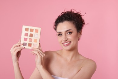 Photo of Smiling woman with eyeshadow palette on pink background