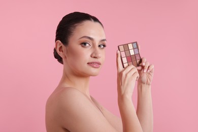 Photo of Woman with eyeshadow palette on pink background