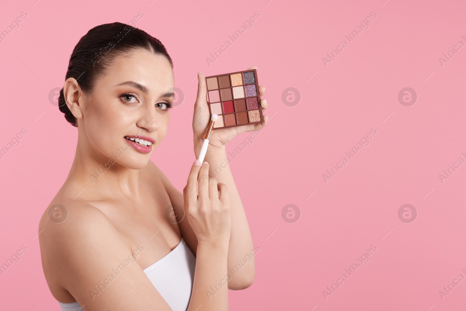 Woman with eyeshadow palette and brush on pink background. Space for text Photo of Woman with eyeshadow palette and brush on pink background. Space for text