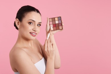 Photo of Woman with eyeshadow palette and brush on pink background. Space for text