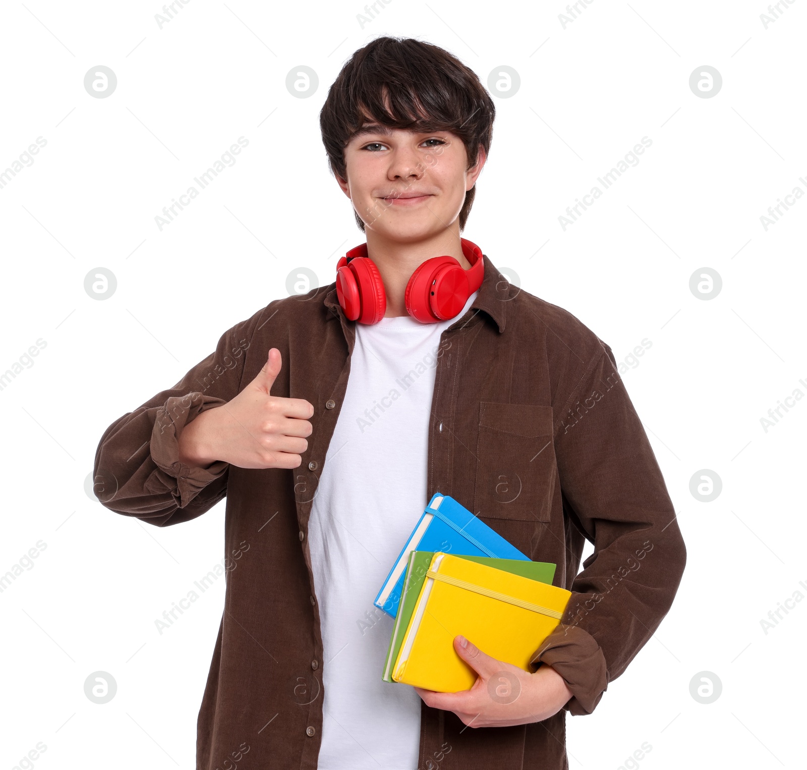 Teenage boy with headphones and notebooks showing thumbs up on white background Photo of Teenage boy with headphones and notebooks showing thumbs up on white background