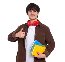 Photo of Teenage boy with headphones and notebooks showing thumbs up on white background