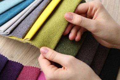 Photo of Woman with samples of different fabrics at wooden table, closeup