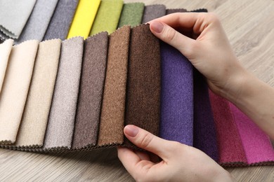 Photo of Woman with samples of different fabrics at wooden table, closeup