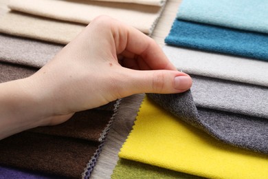 Photo of Woman with samples of different fabrics at wooden table, closeup