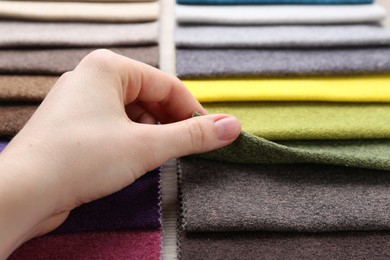 Photo of Woman with samples of different fabrics at wooden table, closeup