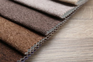 Photo of Samples of different fabrics on wooden table, closeup