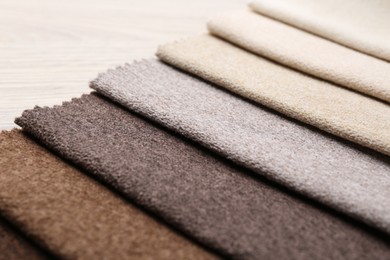 Photo of Samples of different fabrics on wooden table, closeup