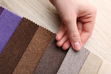 Photo of Woman with samples of different fabrics at wooden table, closeup