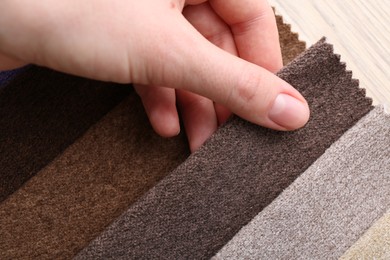 Photo of Woman with samples of different fabrics at wooden table, closeup