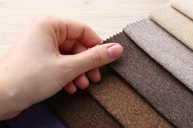 Photo of Woman with samples of different fabrics at wooden table, closeup