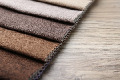 Photo of Samples of different fabrics on wooden table, closeup. Space for text