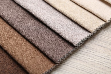 Photo of Samples of different fabrics on wooden table, closeup