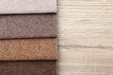 Photo of Samples of different fabrics on wooden table, top view. Space for text