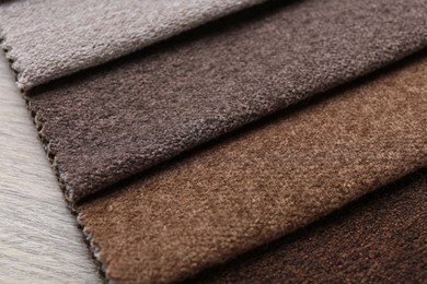 Photo of Samples of different fabrics on wooden table, closeup