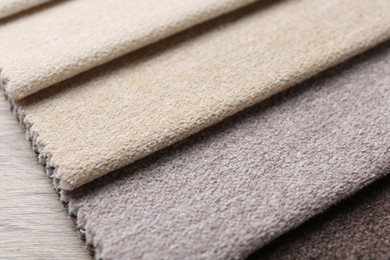 Photo of Samples of different fabrics on wooden table, closeup