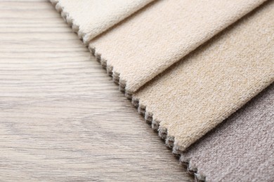 Photo of Samples of different fabrics on wooden table, closeup. Space for text