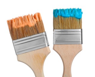 Photo of Brushes with orange and light blue paints isolated on white