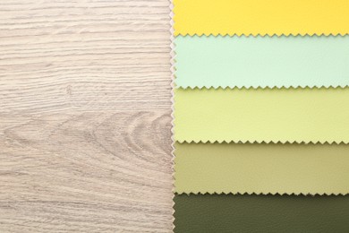 Photo of Samples of different fabrics on wooden table, top view. Space for text