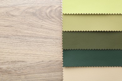 Photo of Samples of different fabrics on wooden table, top view. Space for text