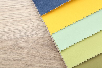 Photo of Samples of different fabrics on wooden table, top view. Space for text