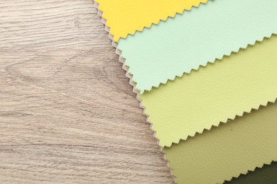 Photo of Samples of different fabrics on wooden table, top view. Space for text