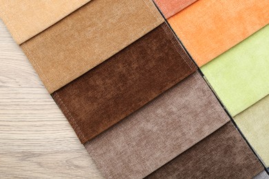 Photo of Samples of different fabrics on wooden table, top view