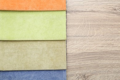 Photo of Samples of different fabrics on wooden table, top view. Space for text