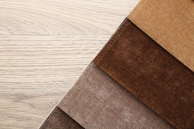 Photo of Samples of different fabrics on wooden table, top view. Space for text