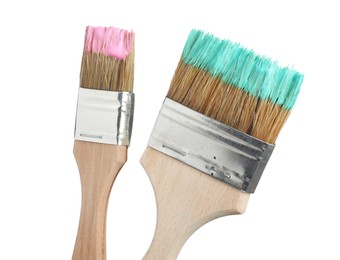 Photo of Brushes with pink and turquoise paints isolated on white