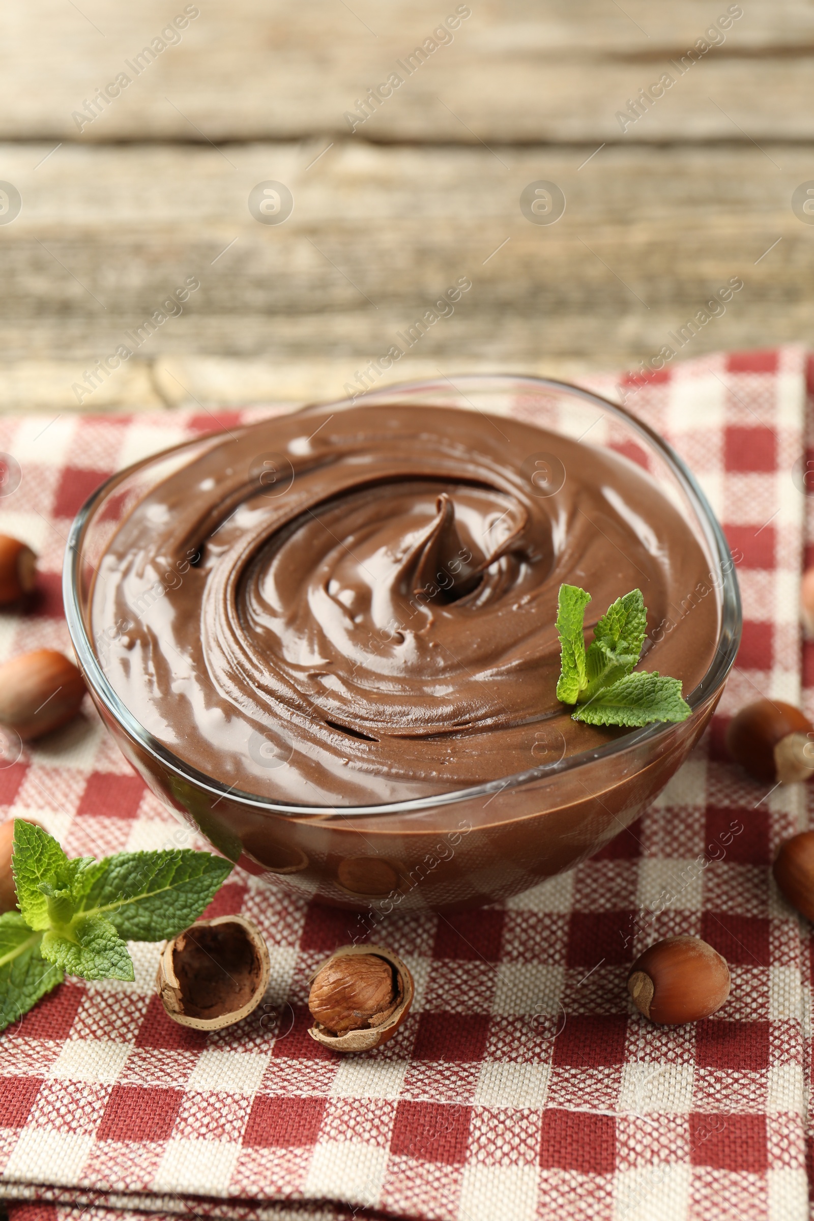 Tasty chocolate spread with mint and hazelnuts on wooden table, closeup Photo of Tasty chocolate spread with mint and hazelnuts on wooden table, closeup