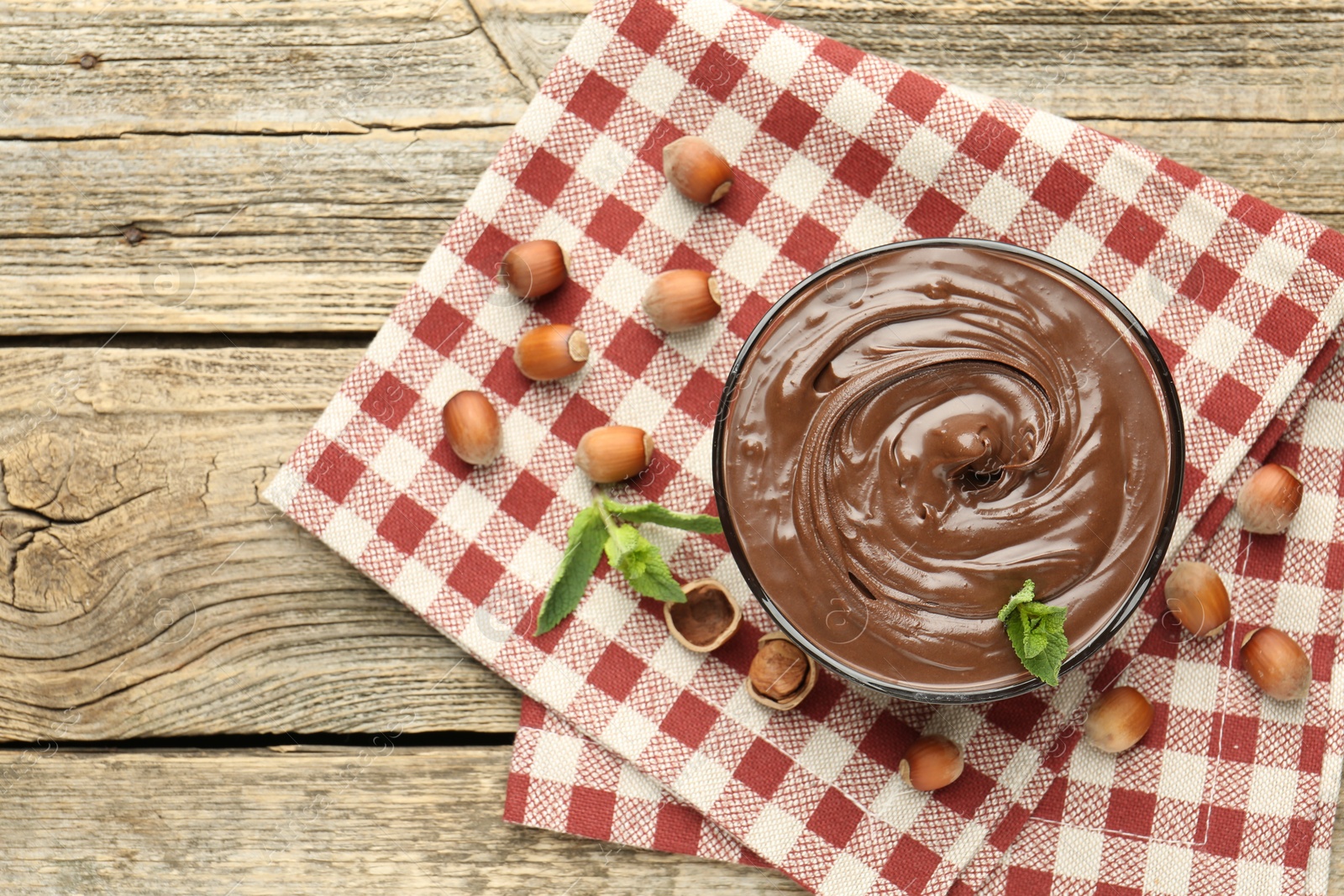 Tasty chocolate spread with mint and hazelnuts on wooden table, flat lay. Space for text Photo of Tasty chocolate spread with mint and hazelnuts on wooden table, flat lay. Space for text