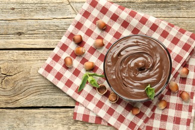 Photo of Tasty chocolate spread with mint and hazelnuts on wooden table, flat lay. Space for text