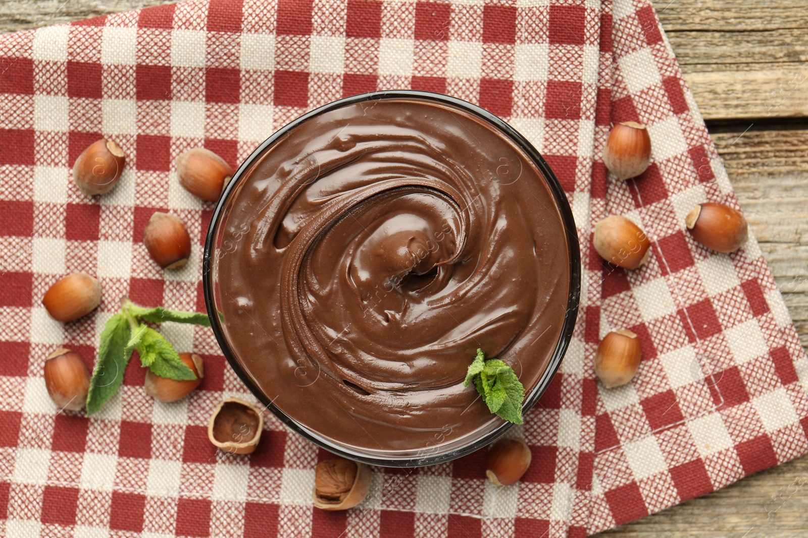 Tasty chocolate spread with mint and hazelnuts on wooden table, flat lay Photo of Tasty chocolate spread with mint and hazelnuts on wooden table, flat lay