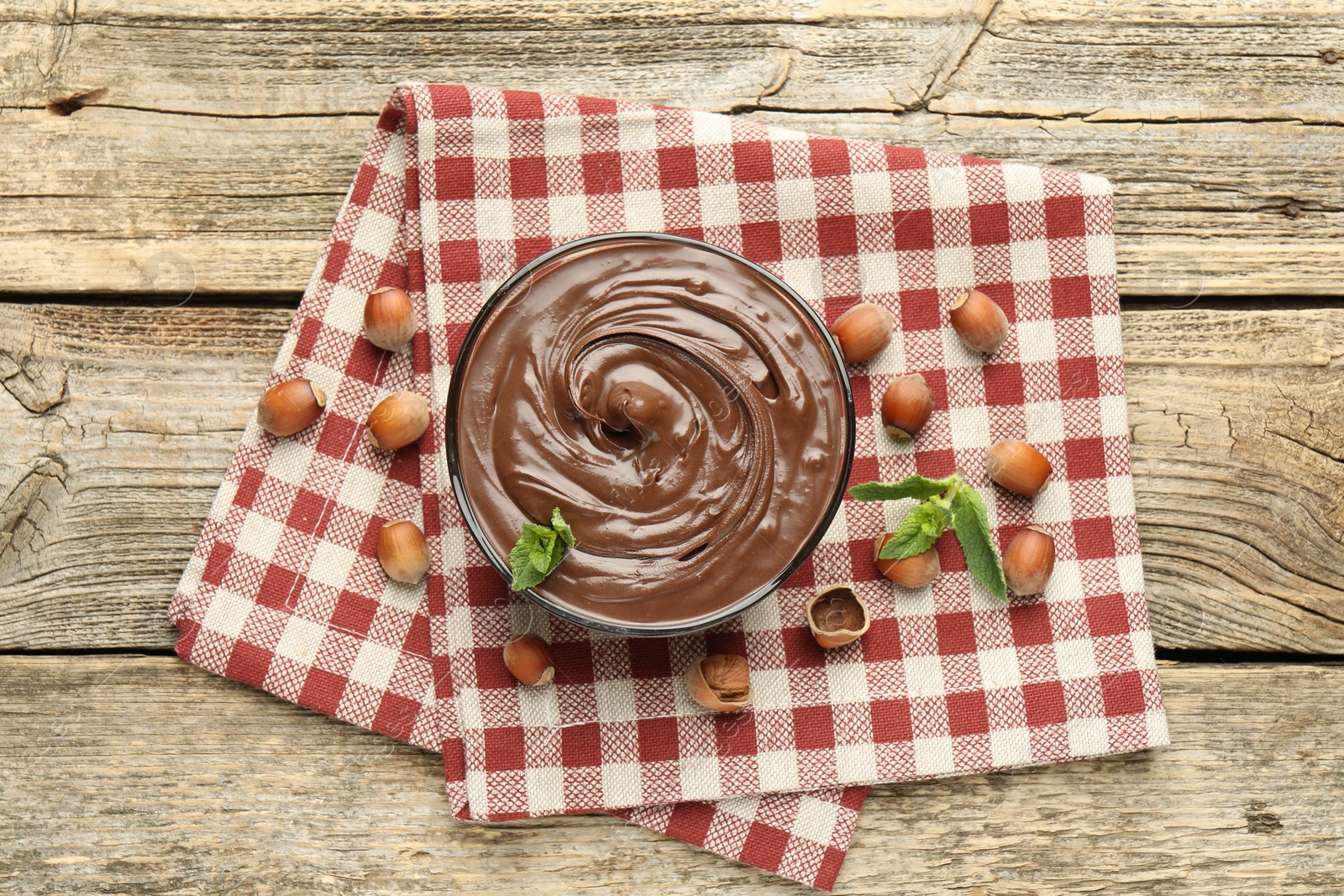 Photo of Tasty chocolate spread with mint and hazelnuts on wooden table, flat lay