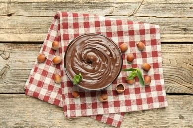 Photo of Tasty chocolate spread with mint and hazelnuts on wooden table, flat lay