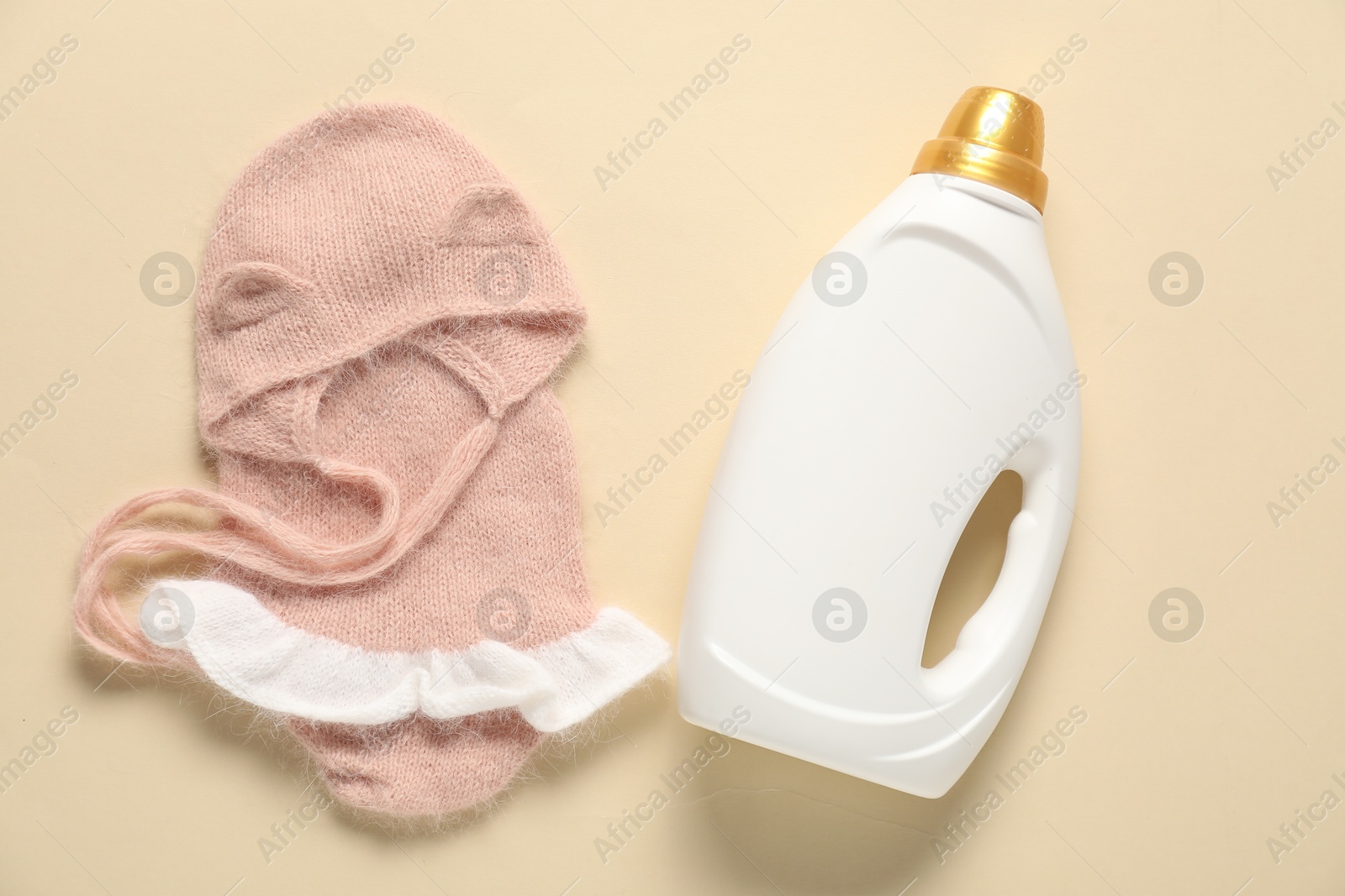 Bottle of fabric softener and baby clothes on beige background, flat lay Photo of Bottle of fabric softener and baby clothes on beige background, flat lay