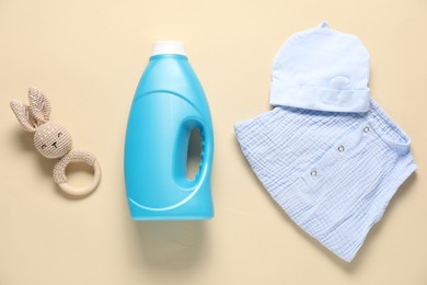 Photo of Bottle of fabric softener, toy and baby clothes on beige background, flat lay