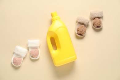 Photo of Bottle of fabric softener and baby socks on beige background, flat lay