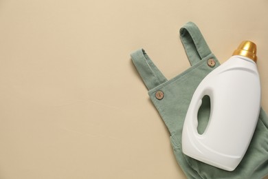 Photo of Bottle of fabric softener and baby clothes on beige background, top view. Space for text