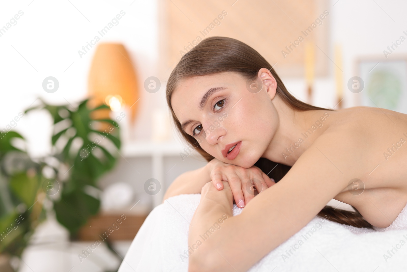 Portrait of beautiful woman on massage couch in spa salon. Space for text Photo of Portrait of beautiful woman on massage couch in spa salon. Space for text