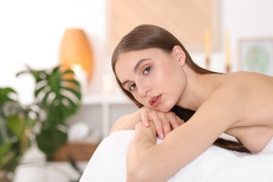 Photo of Portrait of beautiful woman on massage couch in spa salon. Space for text
