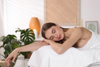 Photo of Beautiful woman relaxing on massage couch in spa salon