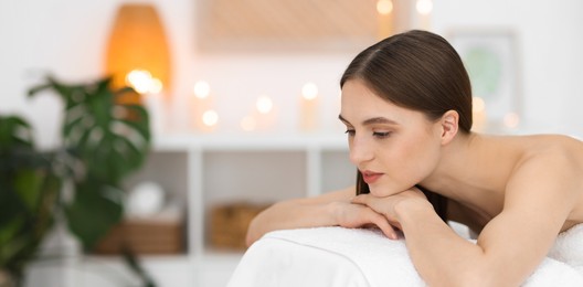 Photo of Beautiful woman relaxing on massage couch in spa salon. Space for text
