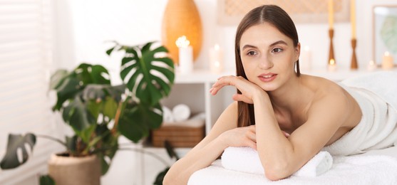 Photo of Beautiful woman relaxing on massage couch in spa salon. Space for text
